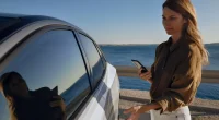 Hand håller mobiltelefon mot bildörr för att låsa upp med digital nyckel