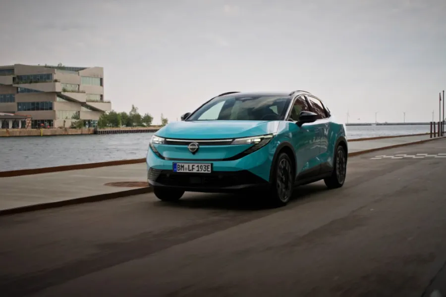 Turkos Nissan LEAF på en väg vid havet